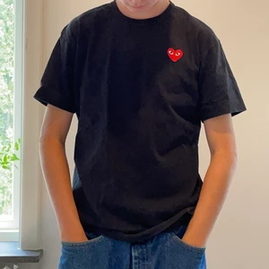 Comme des garcons play T-shirt storlek L - Säljer en Svart Comme des garcons play t-shirt som jag köpt på NK i Göteborg under sommaren 2020. T-shirten är storlek L men passar även M. Tröjan har inga hål eller skador. Skriv om du har mer frågor!