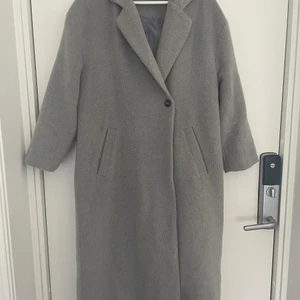 Lång kappa - Säljer min kappa som är köpt på Bubbelroom. Den är i använt skick. En grå snygg kappa som är längre, och en bredare modell. Super bra nu till hösten. Säljer för 200kr eller kom med bud! Den är i storlek 34 men passar även mig som är en 36-38.