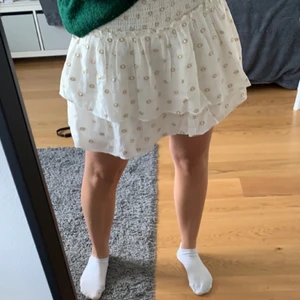 Vit kjol - En jättesöt vit kjol med guld och silver detaljer, använd några få gånger i somras och är i väldigt fint skick, storlek M men passar också S