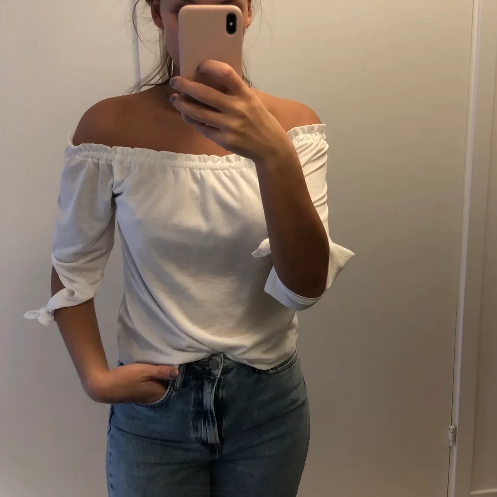 En vit off shoulder topp med knytning på ärmarna från Pull and Bear. Använd 1 gång. . Toppar.