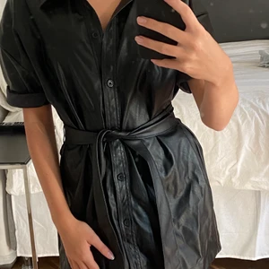 Skinnklänning  - Säljer min svarta snygga skinnklänning med en band i midjan (inte äkta skinn) använd 2-3 gånger. Jättefin och jätteskön, är som ny. Klänningen är från Gina tricot, i storlek 34. Frakt tillkommer🤍