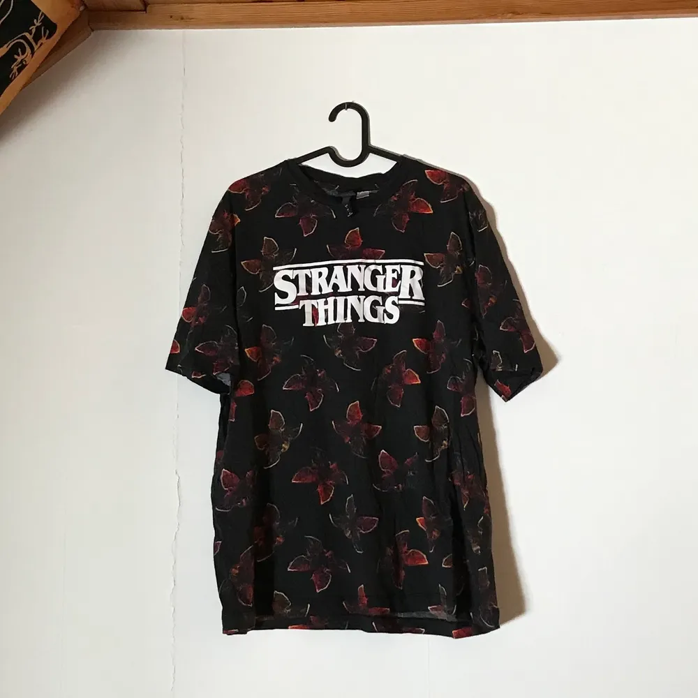 En jättesnygg svart t-shirt med demogorgons på och även ett ”Stranger Things” tryck. Köpt på H&M för jättelänge sedan och den är knappt använd. Perfekt för en stranger things älskare!! T-shirten är i storlek L.. T-shirts.