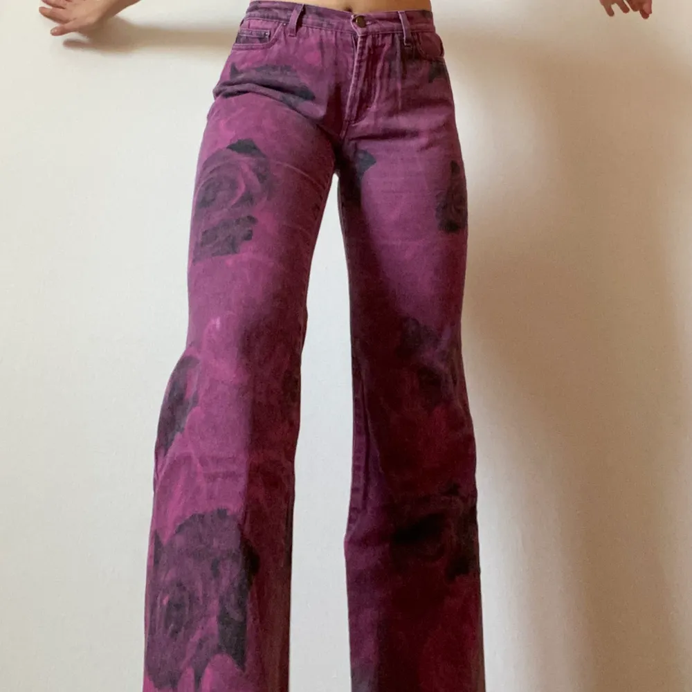 Lila utsvängda byxor med svarta rosor och silver skimmer längst ner. . Jeans & Byxor.