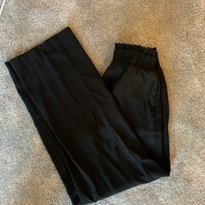 Svarta kostymbyxor  - Svarta kostymbyxor från Nelly med resår i midjan i storlek 34. De sitter väldigt skönt och sitter bra på mig som är strl. 34/36. De går hela vägen ner till marken på mig och jag är 163 cm. Nypris: 329 kr