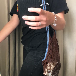 Virkad totebag  - Så söt nät-totebag i brun med blå söm på handtagen. Denna nätväskan är perfekt att ha som shoppingpåse eller för att piffa till en tråkig outfit. Eftersom det är nät så rymmer sjukt mycket mer än vad man förväntar sig också!🤎