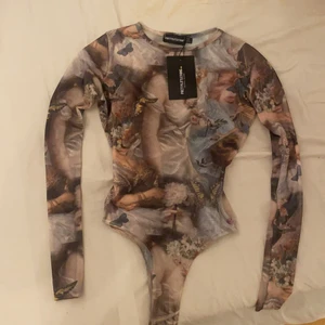Fest tröja - Säljer denna festliga bodyn med en cool design på från prettylittlethings. Bodyn var för liten på mig när jag fick hem den och säljer därför vidare den. Aldrig andvänd💕💕 (kan vara väldig genomskinlig då det är tunt tyg)