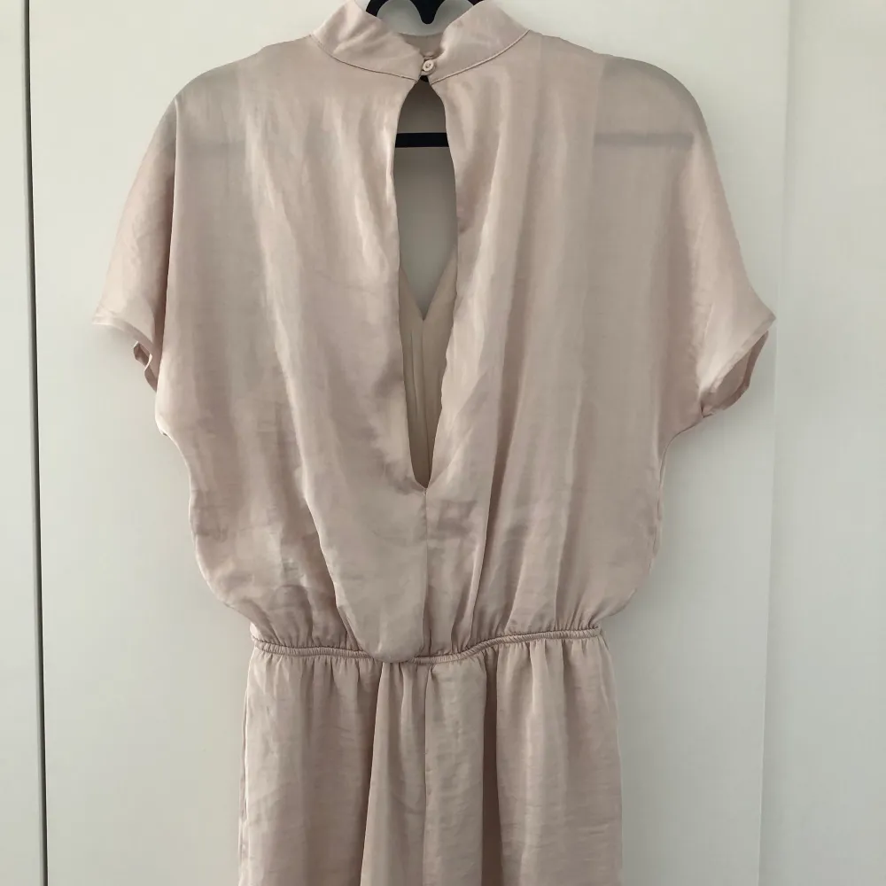 Champangefärgad kort byxdress/jumpsuit från Gina Tricot i strl. 34. Aldrig använd, tags kvar. . Övrigt.