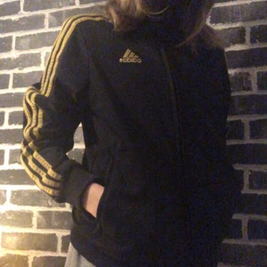 Adidas hoodie - Fin adidas hoodie med guldiga ränder. Hittar ingen specifik stolek men skulle säga att den passar mellan xxs-s! Onvanlig och fin tröja men kommer inte till användning och därför säljer jag den:) kan tänka mig att byta mot något. fler bilder finns så hör av er vid intresse