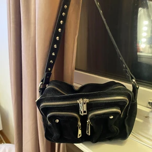Nunoo väska , modell ellie new suede. - En svart nunoo väska som tyvärr inte kommer till användning längre. Det tillkommer ett svart längre band till den om man skulle vilja ha det. Den är i bra skick och inga ”skador” på den så den är iprincip som ny!  Den är väldigt rymlig för att vara en så liten väska så det är väldigt bra !! 