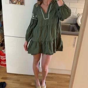 Zara klänning - Säljer en grön Zara klänning med volanger och vita broderade detaljer vid halsringningen och på ärmarna. Klänningen är slutsåld och jättebra skick!🥰🥰