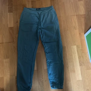 Gröna mjukisbyxor från Dressmann - Säljer ett par gröna mjukisbyxor från Dressmann i storlek L. Byxorna har resår i midjan med snörning och muddar vid bensluten. Perfekta för en avslappnad stil eller hemmamys.