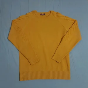 Gul stickad tröja från Turbo - Säljer en snygg gul stickad tröja från Turbo. Tröjan har lång ärm och coola ribbade detaljer längs axlar och ärmar. Perfekt för dig som vill ha en färgklick i garderoben! Rund halsringning och mjukt material.