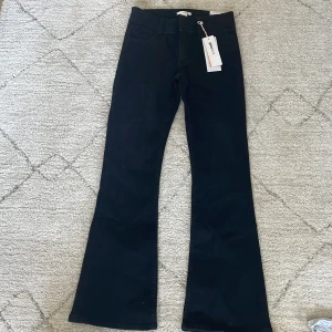Svarta bootcut jeans från mönstrade fickor - Säljer ett par svarta bootcut jeans från Gina Tricot i storlek 158. Byxorna har klassisk femficksdesign och utsvängda ben. Perfekta för dig som gillar en trendig siluett och vill ha ett par stilrena svarta jeans. Mönster på fickorna.