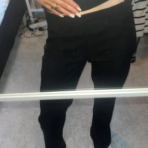 Svarta kostymbyxor med bootcut - Säljer ett par svarta kostymbyxor med bootcut passform. Byxorna har medelhög midja och dragkedja på sidan.
