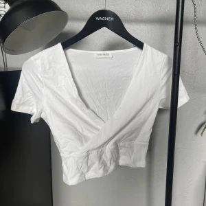 Två pack med en svart och en vit crop top tröja - Säljer en svart och en vit croppad tröja från Even och odd. T-shirten har korta ärmar och en djup v-ringning framtill. Perfekt att matcha med höga jeans eller kjol.