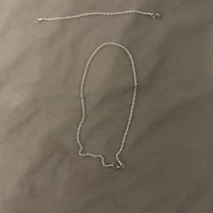 Två silverfärgade armband och kedja  - Säljer  kedja och armband  i silverfärg, en längre och en kortare. Passar perfekt som halsband eller armband. Kedjorna har enkel och stilren design med små länkar.