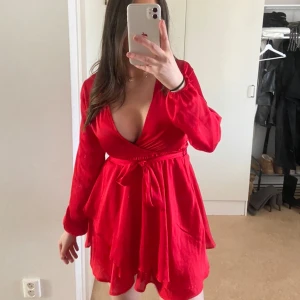 Röd omlottklänning från Linn Ahlborg x NA-KD - Säljer en röd omlottklänning från Linn Ahlborg x NA-KD. Klänningen har lång ärm, v-ringning och knytband i midjan. 