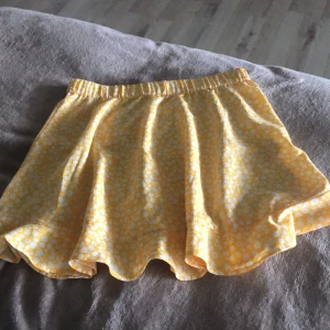 Gul blommig kjol från Vero Moda - Superfin gul kjol från Vero Moda med vitt blommönster och volangkant. Kjolen har resår i midjan och är lätt och luftig – perfekt för varma dagar.