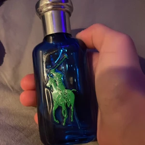 Ralph Lauren Polo Blue 1 herrparfym - Fräsch herrparfym från Ralph Lauren i blå glasflaska med silverfärgad kork. Flaskan har en stor gul siffra 1 på ena sidan och en grön polospelare på andra sidan. Perfekt för dig som gillar sportiga och energiska dofter.20-16