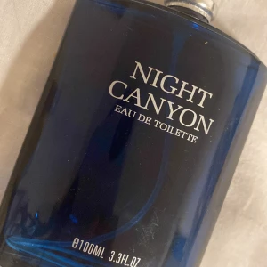 Night Canyon Eau de Toilette 100ml - En stilren parfymflaska i mörkblått glas med silverfärgad kork. Night Canyon Eau de Toilette har en modern och maskulin design, perfekt för dig som gillar fräscha och eleganta dofter. Flaskan rymmer 100 ml.