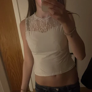 Vit croppad linnetopp med spetsdetaljer - Säljer en vit croppad linnetopp med spets upptill både fram och bak. Toppen är ärmlös och har en rund halsringning. Perfekt för sommaren och enkel att matcha med jeans eller kjol.🥰 priset går att diskutera 