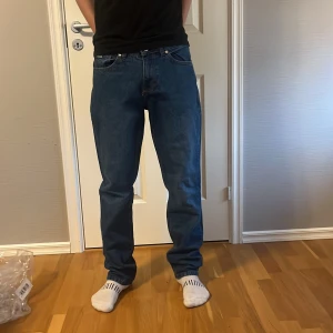 Blå jeansbyxor (loose fit) - Säljer ett par klassiska blå jeansbyxor med rak passform och normal midja. Jeansen har 4 fickor, dragkedja och knapp framtill. Perfekta för en enkel och stilren look.( loose fit )