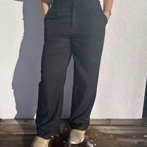 Svarta kostymbyxor från H&M - superfina svarta vida kostymbyxor från H&M. Sitter fint på kroppen och har pösiga ben. Skicket är mycket fint. storleken är 36 vilken ser ut att överens stämma då modellen brukar ha 36/38.