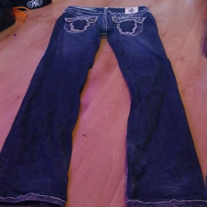  Laguna beach Mörkblå jeansbyxor med nitar och broderi från laguna beach  - Laguna beach Säljer ett par mörkblå jeansbyxor från laguna blue med unika bakfickor dekorerade med nitar, broderier och detaljerade sömmar. Byxorna har raka ben och låg midja, perfekt för dig som gillar statement-jeans.