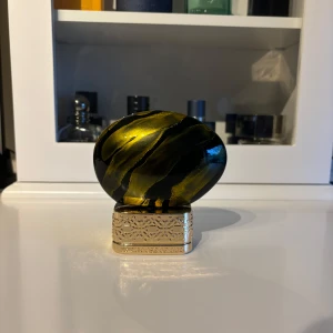 Dates Delight Eau de Parfum från House of Oud - Unik parfymflaska från House of Oud i svart och guld med ett konstnärligt, marmorerat mönster. Flaskan har en lyxig, oval form och guldfärgad botten med ingraverade detaljer. Innehåller 75 ml Eau de Parfum, tillverkad i Italien. Det är 50/75 kvar