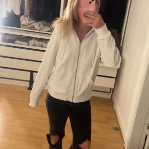 Vit hoodie med dragkedja - Säljer en enkel och stilren vit hoodie med dragkedja framtill och fickor på sidorna. Perfekt för en avslappnad look och passar till det mesta. Mjuk och skön att ha på sig.