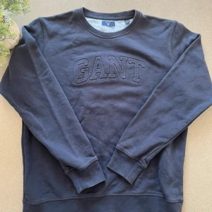 Mörkblå sweatshirt från GANT -  Brand: GANT 📐 Size: M 13-14 years 🎨 Color: Navy Blue 🧵 Material: 90% Cotton, 10% Polyester  👕 Fit: Regular 📏 Length: Regular ⭐ Condition: Like new, Worn a few times ⚠️ Defects: None