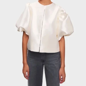 By malina blus ”Cleo” - Säljer en elegant vit blus från By Malina i glansigt satinmaterial. Blusen har rund halsringning och stora puffärmar som ger en trendig siluett. Obs, blusen har sminkfläckar runt halsen, men som enkelt går bort vid tvätt. Därav av det låga priset (ord.pris 2200). 