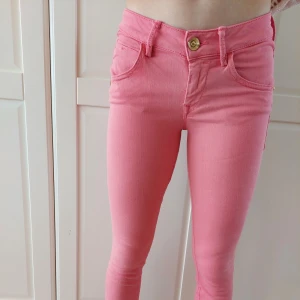 Rosa jeans från Fornarina - Säljer ett par snygga laxrosa jeans från italienska Fornarina. De har en klassisk femficksdesign med knappar och dragkedja fram. Stretch s.k perfect shape och modellen heter Eva. Perfekta för att liva upp garderoben med lite färg!