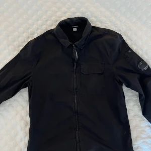 Svart overshirt jacka från C.P. Company - Säljer nu min C.P company overshirt, jackan är i bra skick och perfekt nu inför sommaren. Inga synliga defekter. Kontakta mig för fler frågor (Pris kan diskuteras) ⭐️ Passar perfekt med ett par snygga jeans och en grå hoodie🔥