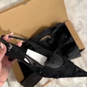 Svarta pumps med spetsig tå från MNG - Stilrena svarta pumps från MNG med spetsig tå och låg klack. Skorna har meshdetaljer och är dekorerade med svarta paljetter