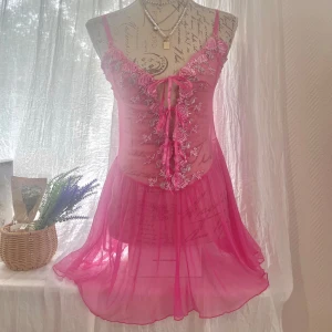 Rosa spetsklänning med broderi - Superfin kort rosa klänning i mesh med tunna axelband och v-ringning. No brand. Passar storlek 36-38. Dockan har storlek 36.