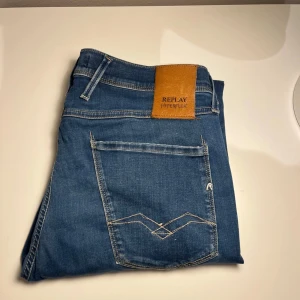 Replay anbass hyperflex - REPLAY ANDBASS!Snygga blå jeans från Replay Hyperflex med klassisk femficksdesign och knappgylf. De har en stilren look med diskreta sömmar och en läderpatch med logga på baksidan. Perfekta för en avslappnad stil.Storlek 32. Nypris 1700kr. (Säljer då dom var små på mig)