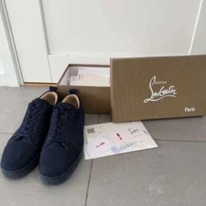 Mörkblå mockasneakers från Louboutin - Snygga mörkblå sneakers från Christian Louboutin i mjuk mocka. Klassisk rund tå, platt sula och diskret snörning. Perfekta för dig som vill ha en stilren och lyxig look med exklusiv känsla. Kop10a