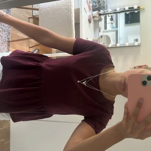 Vinröd topp med kort ärm - Supersöt topp med korta ärmar och rund hals. Modellen är kort och har en volang 