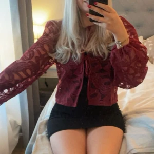 Vinröd spetskofta med knyt - Supersnygg vinröd kofta i spets med transparenta, vida ärmar och knyt framtill. Storlek xs men passar också mig som är S. Använd en gång.