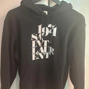Saint Laruent Hoodie - Saint Laurent hoodie med trycket ”1891” otroligt snygg hoodie, ända defekten är att en av metall bitarna lossnat därför är priset sänkt. | Storlek S | Hör av dig vid frågor👊