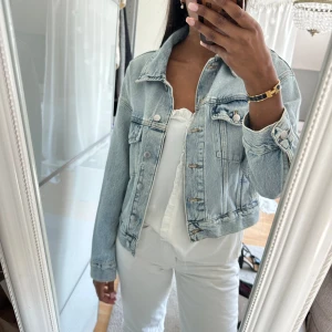 Ljusblå jeansjacka från H&M  - Säljer en  ljusblå jeansjacka från H&M i storlek XS. Jackan har en rak passform, knappar framtill och två bröstfickor. Aldrig använd! 