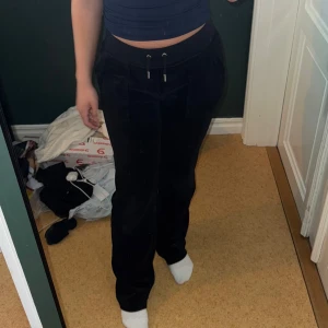 Svarta juicy byxor  - Svarta juicy byxor. Använda men i väldigt fint skick. Byxorna har raka ben, fickor fram och bak med silvriga detaljer. 