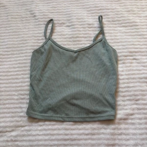 Ljusgrön ribbad linnetopp från SHEIN - Snygg ljusgrön ribbad linnetopp från SHEIN i storlek XS. Toppen har smala axelband och croppad passform, perfekt till jeans eller kjol. Mjuk och stretchig bomullsblandning som sitter skönt mot kroppen.