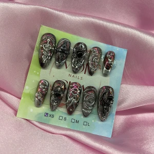 GalaxyDrip (XS);Medium Almond - Unika gelé press-on naglar i svart och silver med 3D-effekt, swirlmönster och hjärtformade detaljer. Naglarna har en glittrig finish med inslag av rosa och är formade i en medium almond-stil. Perfekt för dig som vill sticka ut med coola och kreativa naglar. I storlek XS: 14 mm, 11 mm, 11,5 mm, 10 mm, 8 mm 