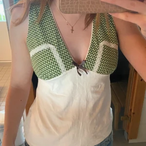 linnetopp med rosett y2k - Supersöt linnetopp med grönmönstrad överdel, vit nederdel och spetsdetaljer. Djup v-ringning och liten brun rosett framtill. Sitter som storlek S! Två små fläckar som är knappt synliga!! 🤍 y2k, coquette 