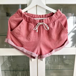 Dassrosa lågmidjade mjukisshorts - Ett par dassrosa lågmidjade mjukisshorts med snörning i midjan i storlek S från H&M Divided som jag fick (i samma skick!) för några år sedan men som aldrig har kommit till användning. Dom är mer ljus korall/aprikosfärgade i verkligheten än på bild och något noppiga och har en gul aktig fläck bak som tyvärr inte gick bort i tvätten. FÖRST TILL KVARN!