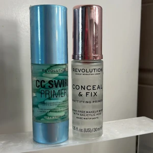 2 primers från Revolution - Två primers från Revolution: CC Swirl Primer med blått och vitt swirlmönster, vitamin C och hyaluronsyra, samt Conceal & Fix Mattifying Primer i genomskinlig flaska med silvrigt lock. Båda är 30 ml och perfekta för att förbereda huden innan smink., båda är endast testade en gång 