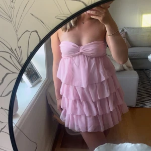 Rosa volangklänning axelbandslös - Supersöt rosa kortklänning med flera lager volanger och axelbandslös design. Klänningen är endast använd 2 ggr.🩷Inga defekter