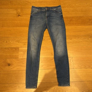 Blå jeans från vero Moda  - Snygga blå skinny jeans från vero Moda  med klassisk femficksdesign och ljusa slitningar på låren. Jeansen har normal midja och är tillverkade i stretchig bomullsdenim för en bekväm passform. Perfekta till sneakers eller boots.